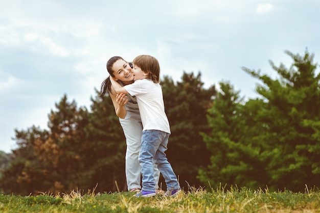 魅力的な若い息子の頬にキスする愛情深い母親。トーン画像