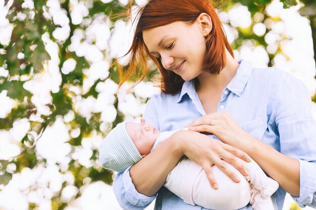 Loving mother with her newborn baby on her arms Beautiful mom with a newborn child on nature