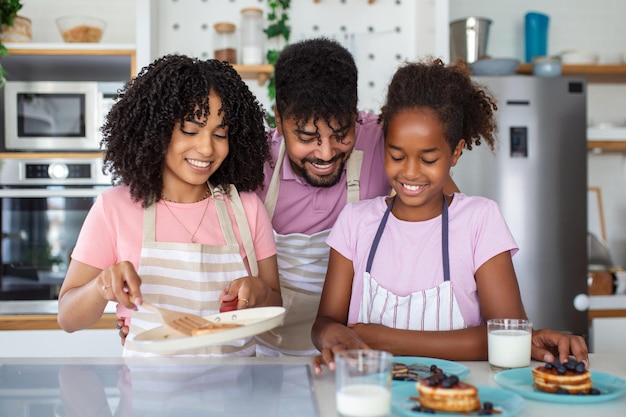 Любящие родители делают вкусную сладкую выпечку на завтрак с взволнованной маленькой дочерью