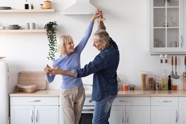 Loving senior couple having fun in kitchen dancing