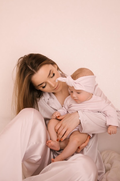 Loving smiling young mother with her newborn daughter on a light background