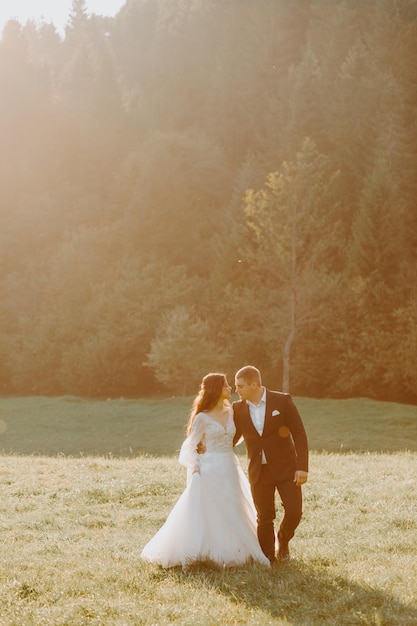 Loving wedding couple kissing in mountains at sunset. Portrait of bride and groom