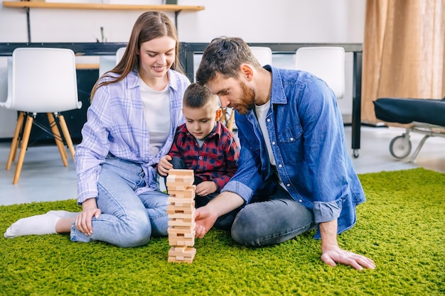 Loving young caucasian family with a boy sitting on the living room floor playing with bricks