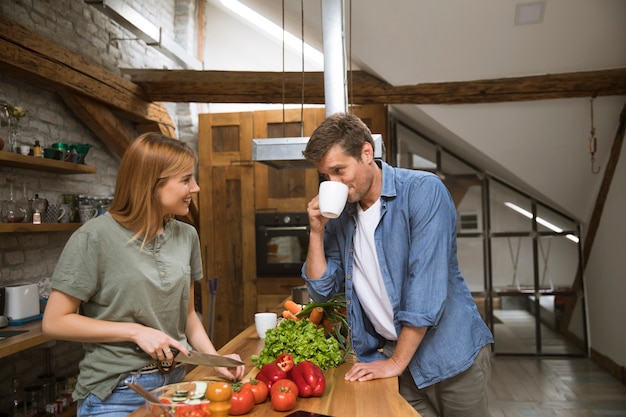 Loving young couple cutting vegetables together in rustic kitchen