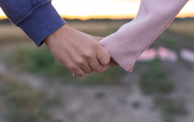 Photo loving young couple holding hands. hands of a girl and a guy close-up.