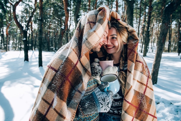 愛する若いカップルが雪に覆われた森の山で休んでいます。ジョイントレストのコンセプト