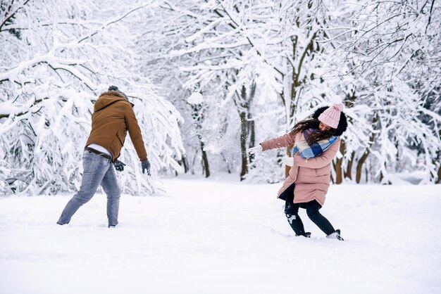 冬の公園で雪玉で遊ぶ愛情のある若いカップル