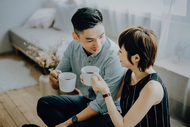 Photo 恋愛 の ある 若い 夫婦 が リビング で 休息 し,コーヒー を 飲み,喜び に っ て 喋っ て いる