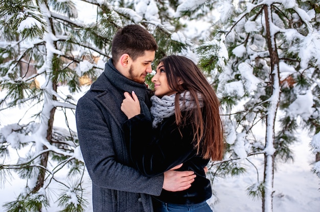 Loving young couple resting in a snowy forest. Hug and kiss. vacation concept