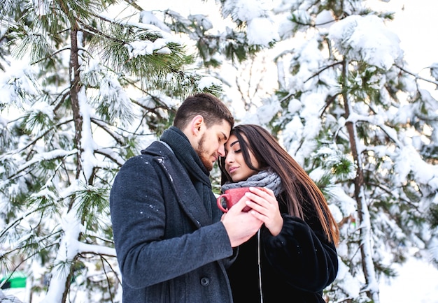 Loving young couple resting in a snowy forest. Hug and kiss. vacation concept