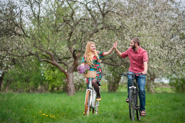 春の庭で自転車に乗って愛する若いカップル