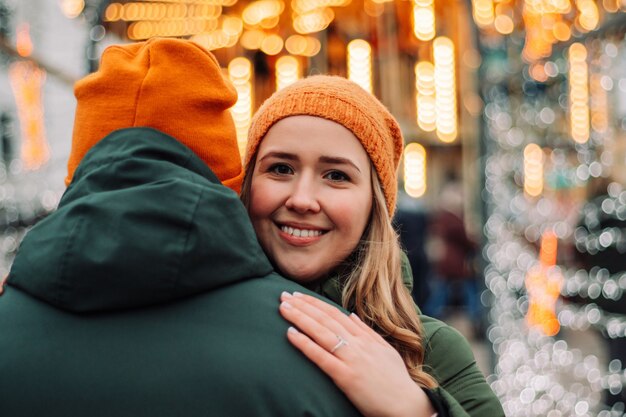 Photo loving young couple standing together outdoors among garlands at winter season