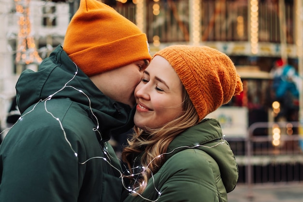 Loving young couple standing together outdoors among garlands at winter season