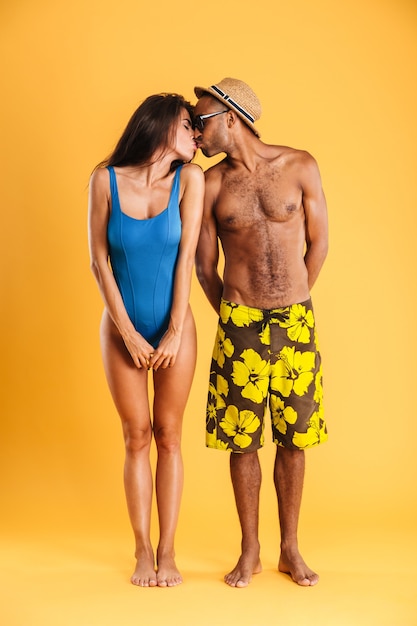 Loving young couple in swimwear kissing isolated on the orange wall