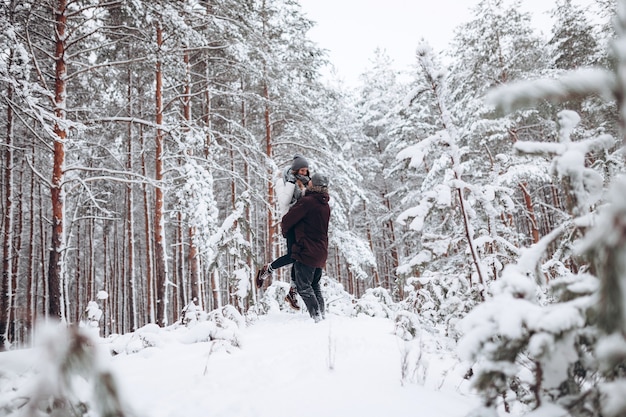 Loving young couple walks in a beautiful snowy forest in winter