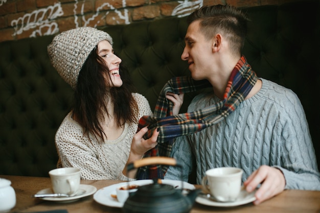 Loving young couple in winter alerts sitting in a cafe and drinking tea