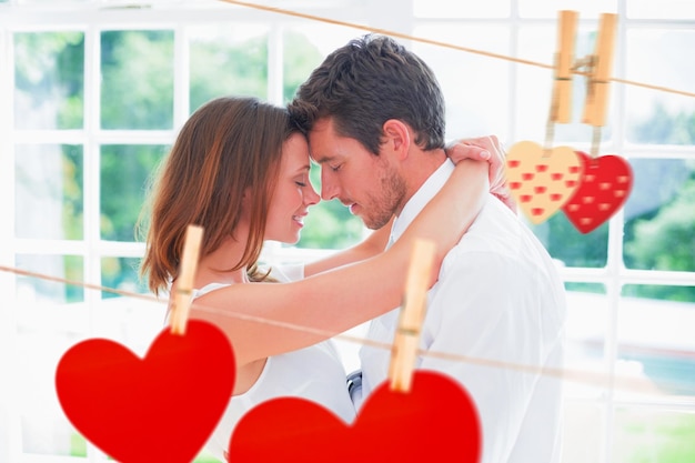 Loving young couple with arms around against hearts hanging on the line