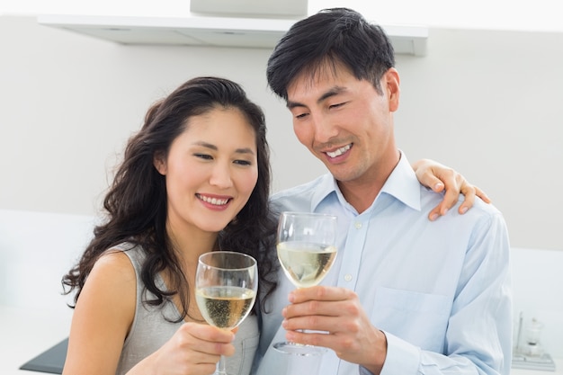 Loving young couple with wine glasses in kitchen