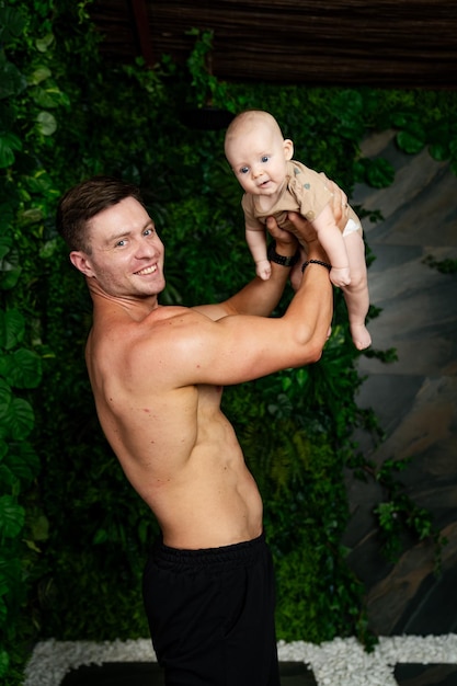 Loving young happy father with baby Muscular man playing with newborn baby