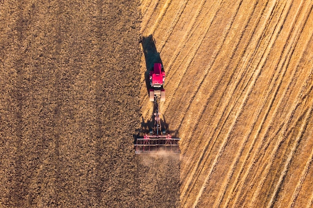 Low altitude aerial top down photo of meadow and farmer in tractor cutting the grass field after this cut grass can dry and be picked up so it can be used as animal fodder for cows