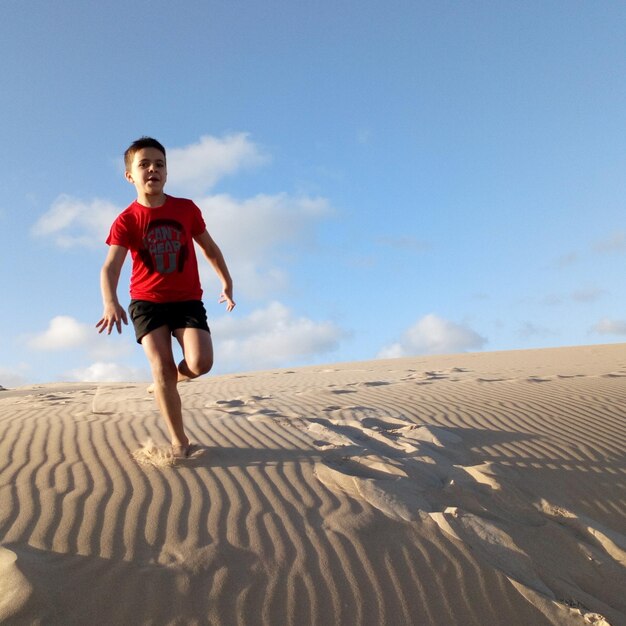 Photo low angle of boy running down dune