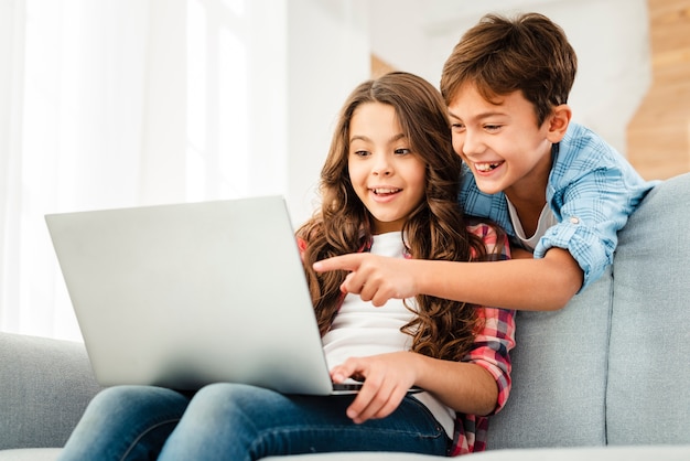 Foto fratello di angolo basso che indica al computer portatile