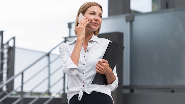 Foto donna di affari di angolo basso che parla sul telefono