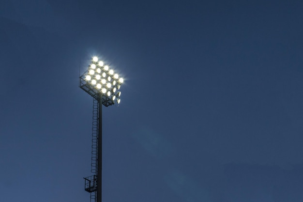 Low angle closeup shot of stadium lights under a dark blue sky