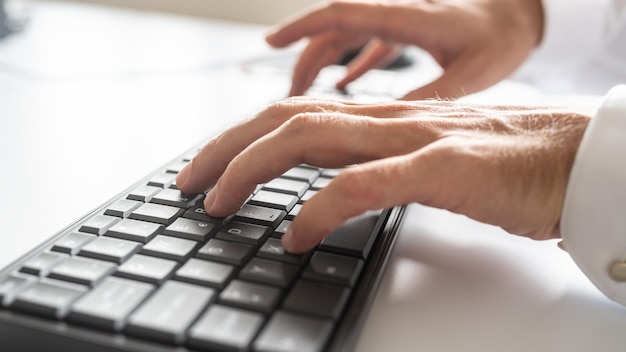 Foto vista ingrandita ad angolo basso della mano maschile utilizzando la tastiera del computer nera