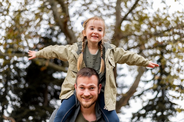 Photo low angle father carrying girl on shoulders