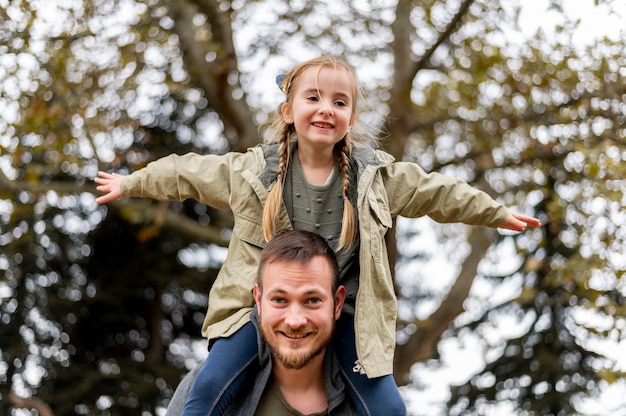 Foto padre ad angolo basso che porta la ragazza sulle spalle