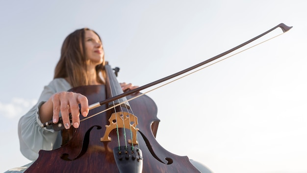 Foto basso angolo di musicista femminile che suona il violoncello