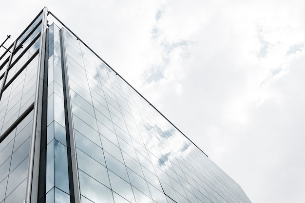 Low angle glass building with clouds