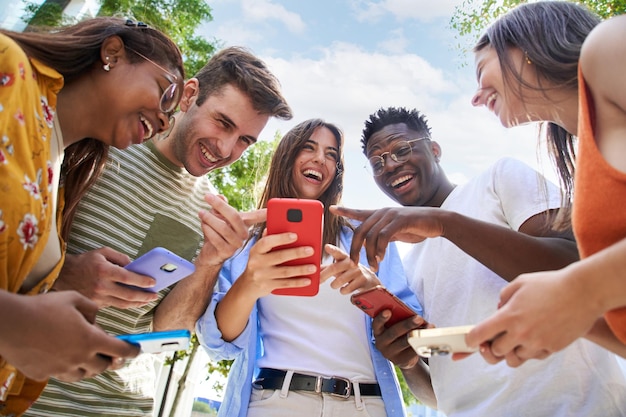 low angle of a group of young teenagers holding cell phones surprised faces looking at the screen