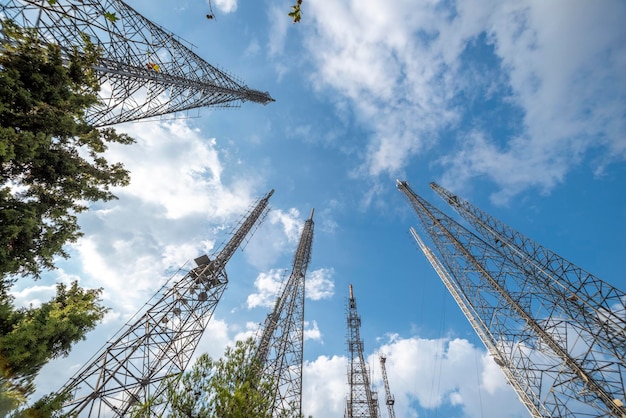 Low angle image of metallic communication towers with blue sky and some clouds