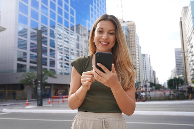 Low angle image of young woman using mobile phone in metropolis avenue