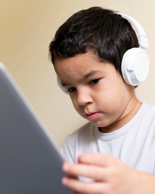 Photo low angle of little boy using laptop with headphones