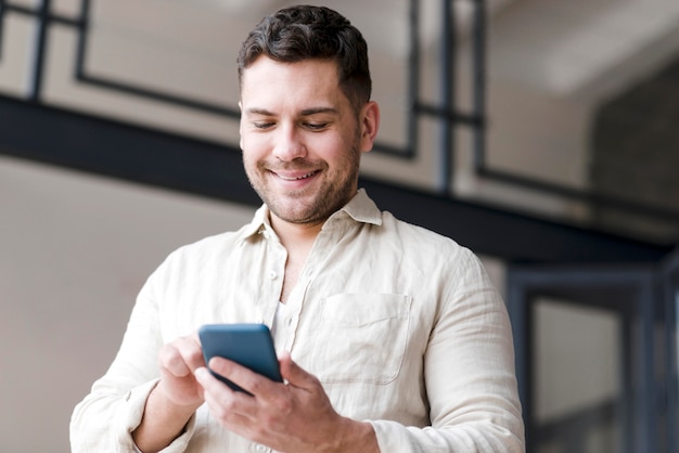 Smartphone della tenuta dell'uomo di angolo basso