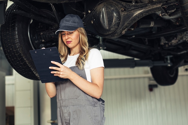 Foto donna del meccanico di angolo basso che ispeziona automobile