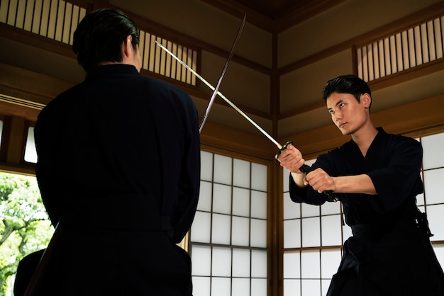 Photo low angle men fighting with swords