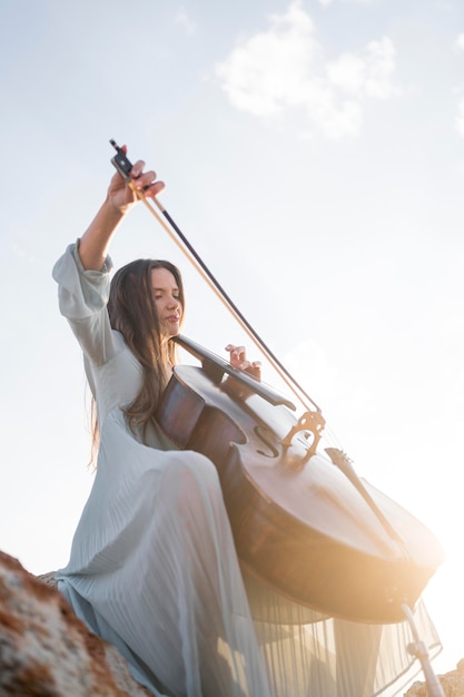 Foto basso angolo di musicista che suona il violoncello con copia spazio