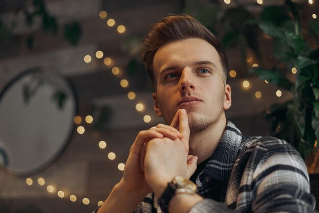 Low angle of pensive male freelancer thinking about new project and looking away in cafe