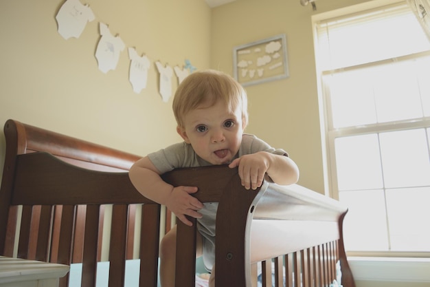 Low angle portrait of boy sitting on bed at home