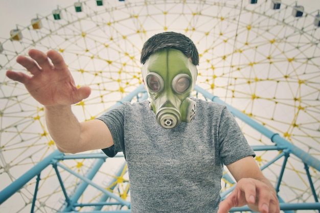 Foto ritratto ad angolo basso di un uomo che indossa una maschera antigas contro la ruota gigante