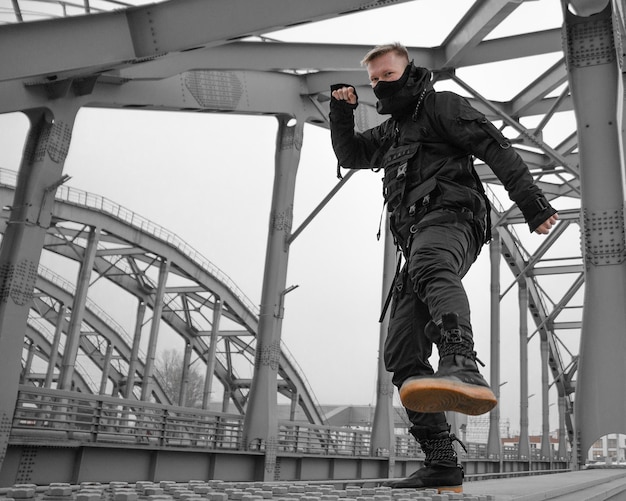 Photo low angle portrait of ninja man practicing martial arts on bridge against sky