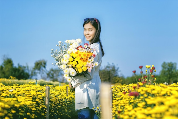 Low angle portrait of smiling woman holding bouquet against clear sky