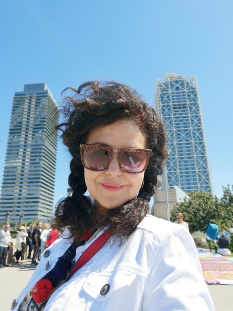 Photo low angle portrait of smiling woman wearing sunglasses against clear sky