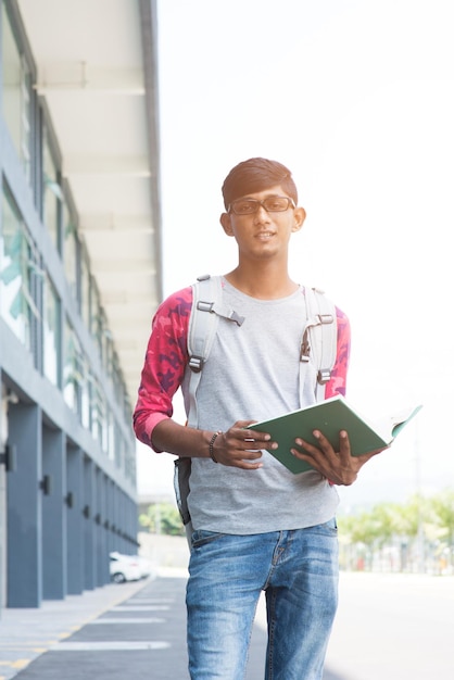 Photo low angle portrait of young man with book standing on road against clear sky