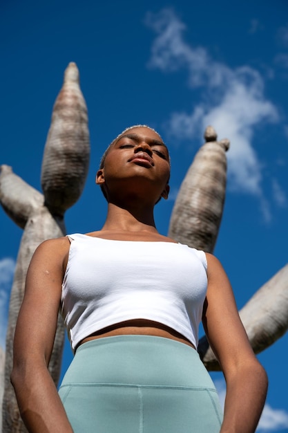 Low angle of relaxed black woman standing with closed eyes against dragon tree