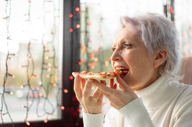 Low angle senior female enjoying pizza slice